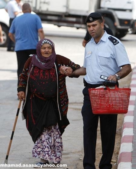 صورة بألف كلمة: ضابط فلسطيني يساعد عجوزا